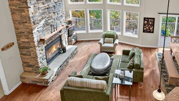 A spacious living room with a stone fireplace, large windows, and a cozy seating area.