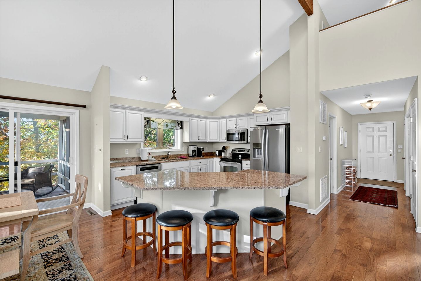 Una cocina amplia con una isla grande, taburetes de madera y una zona de comedor con mesa y sillas.