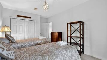 Ein Schlafzimmer mit zwei Betten, einem Schminktisch, einem Kleiderschrank und einer Kandelaber.