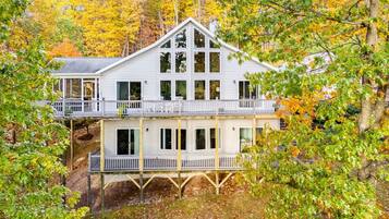 Ein zweistöckiges Haus mit Balkon im oberen Bereich, umgeben von Bäumen mit Herbstlaub.