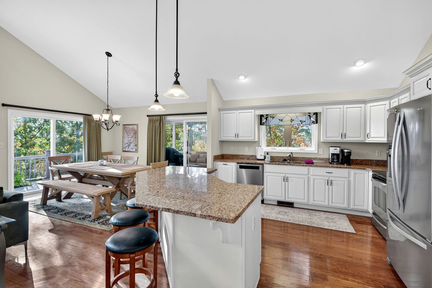 A modern kitchen with a central island, stainless steel appliances, and a dining area with a view.