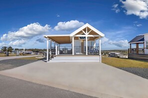 A covered pavilion with a sloped roof, a concrete walkway leading to it, and bicycles parked nearby. - Hill Country Tiny Home Retreat with Resort Amenities Near Fredericksburg, TX (Fredericksburg)