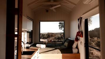 A modern interior with a large window, a sofa, a dining area, and a kitchen.