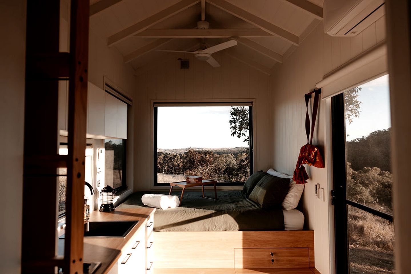 A modern interior with a large window, a sofa, a dining area, and a kitchen.