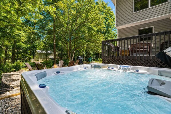 Ein Whirlpool im Freien, umgeben von Bäumen und einer Terrasse.