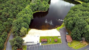 Ilmakuva puistosta, jossa on lampi, huvimaja ja pysäköintialue.