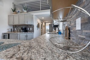 Eine moderne Küche mit Granitarbeitsplatten, einem eingebauten Backofen und einer Edelstahl-Dunstabzugshaube.