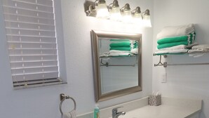 A bathroom with a toilet, sink, mirror, towel rack, and a window with blinds. - 2-Min Walk to Beach · 1BR Duplex w/ Private Lot (Redington Shores)