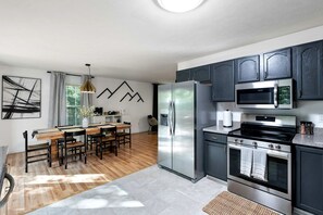A modern kitchen with a central island, stainless steel appliances, and dark cabinetry.