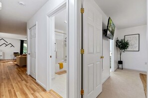 A modern interior with a wooden floor, white walls, and a large mirror.