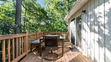 A wooden deck with a table and chairs, surrounded by trees.