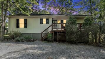 A single-story house with a front porch, a staircase leading to a second level, and a gravel driveway.