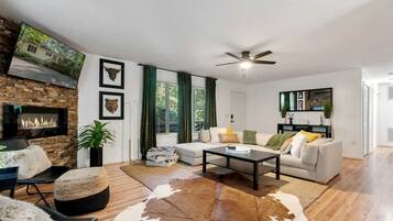 A living room with a fireplace, a sofa, a coffee table, and a cowhide rug.