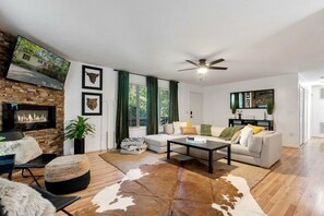 A living room with a fireplace, a sofa, a coffee table, and a cowhide rug.