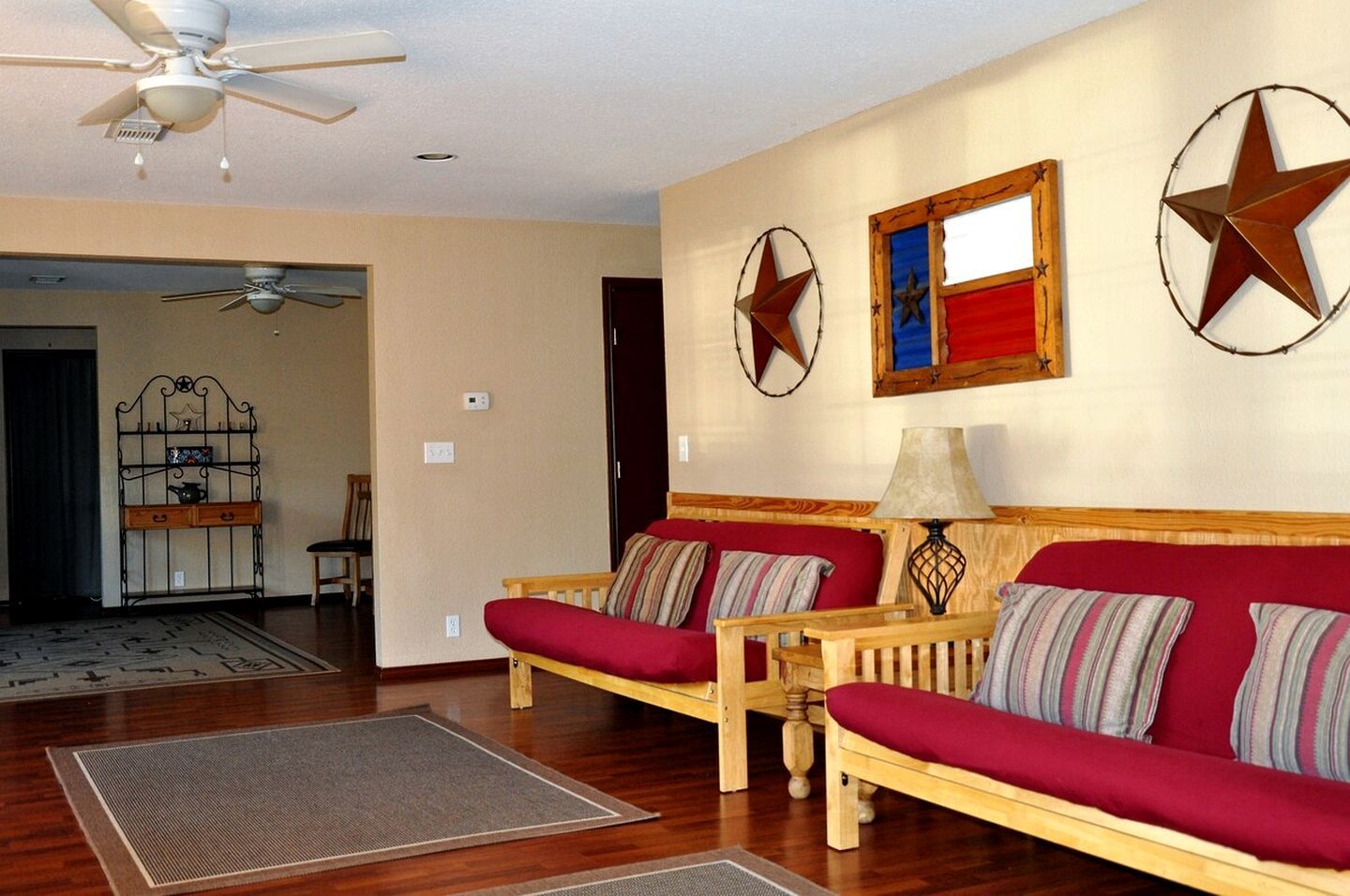 A living room with two sofas, a ceiling fan, and decorative star wall art.