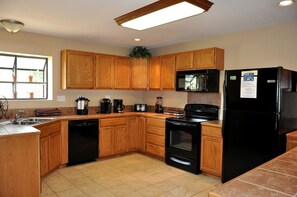 A kitchen with wooden cabinets, a black refrigerator, a microwave, a stove, and a dishwasher. - Spacious Lakefront Home with Beach Access and Sports Courts for Fun-Filled stays in Buchanan Dam, Texas (Buchanan Dam)