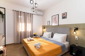 A hotel room with a bed, bedside tables, a wall-mounted air conditioner, and a window with curtains. - Ria Oasis Residence, Luxury 3-Bedroom Apartment with Private Pool (Agios Nikolaos)