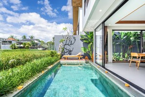 A modern pool area with a lounge chair, a wooden bench, and a view of the surrounding landscape. - Kumarajiva B05 (Gianyar)