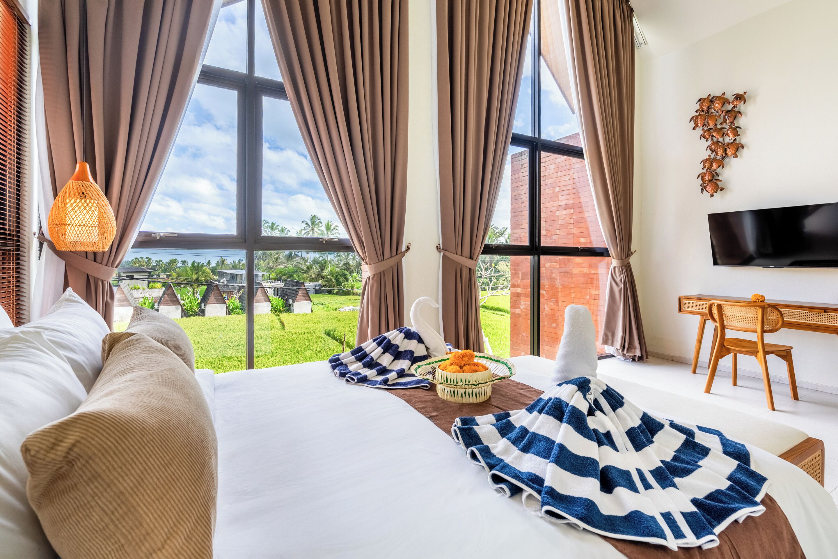Habitación de hotel con cama, televisor, escritorio y vista a zonas verdes.