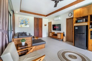 A modern living room with a sofa, a TV, a refrigerator, and a dining area. - Kumarajiva B05 (Gianyar)