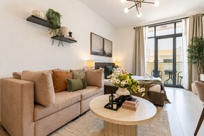 Ein modernes Wohnzimmer mit einem beigefarbenen Sofa, einem runden Couchtisch und einem großen Fenster mit Vorhängen.