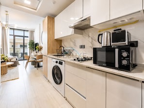 Eine moderne Küche mit Waschmaschine, Mikrowelle und Wasserkocher.