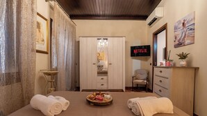 Habitació d'hotel amb llit, barra minibar, televisió i un quadre a la paret.