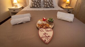 Un llit ben fet amb una decoració en forma de cor, dues taules de nit amb làmpades i un arranjament de coixins florals.