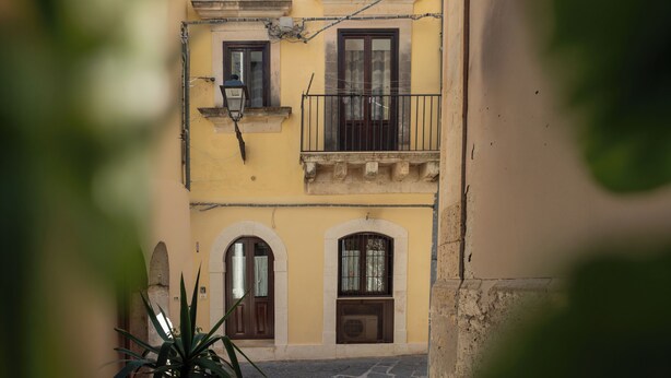 Un edifici amb portals d'arc, un balcó i vista al carrer.