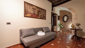 Habitació amb un sofà gris, un quadre, un arc de pedra i un paviment de rajoles.