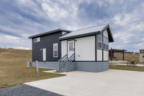 Una casa moderna a due piani con facciata grigia, una porta bianca e un piccolo portico.