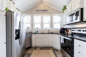 A modern kitchen with white cabinetry, stainless steel appliances, and a sign that reads 'KITCHEN.' - Stylish and Comfortable Tiny Home Getaway with Resort-Style Amenities and Pool Near Fredericksburg, TX (Fredericksburg)