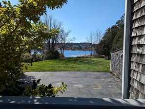 Vista de un lago desde una propiedad residencial con un camino de entrada pavimentado que lleva a una puerta de madera.