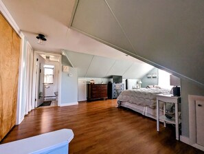 A bedroom with a sloped ceiling, a bed, a dresser, and a desk. - Cozy Waterfront Cottage with Private Beach and Fire Pit Near Gouldsboro, Maine (Gouldsboro)