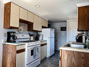 Una cocina compacta con gabinetes de madera, estufa, refrigerador y pileta.