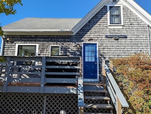 A wooden cottage with a blue door, a small window, and a sign indicating its name. - Cozy Waterfront Cottage with Private Beach and Fire Pit Near Gouldsboro, Maine (Gouldsboro)