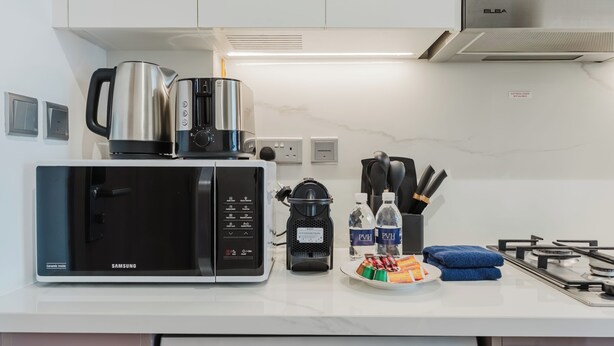 A modern kitchen with a Samsung microwave, an Elba coffee maker, and a gas stove. - PVH - Azizi Riviera 37 Vibrant Studio (Dubai)