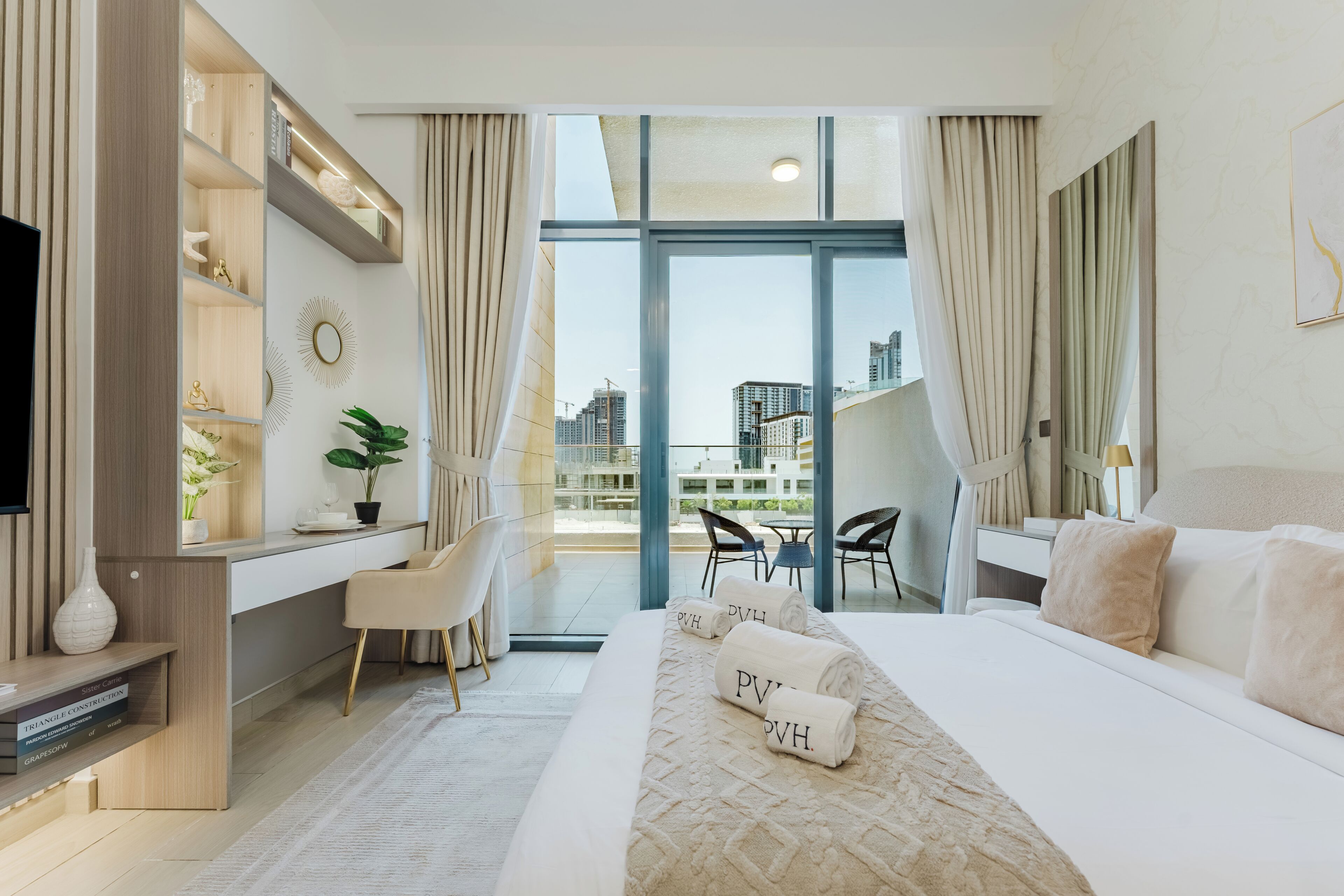 A modern hotel room with a large bed, a desk, and a view of the cityscape.