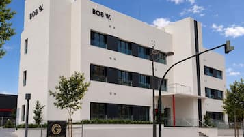 Een modern gebouw met de naam 'BOB W.' op de gevel, met een plat dak, grote ramen en een hekwerk.
