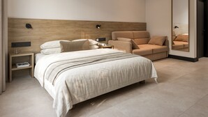 Un dormitorio moderno con una cama grande, una mesita de noche, una lámpara de lectura y un sofá.