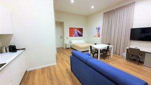 Een moderne hotelkamer met een sofa, een bed, een eettafel met stoelen, een bureau en een televisie.