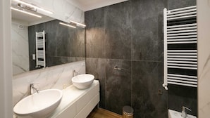 Een moderne badkamer met twee wastafels, een grote spiegel en een handdoekrek.
