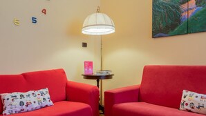 Ein Zimmer mit zwei roten Sofas, einem kleinen Tisch mit einer Lampe und einem Bild an der Wand.