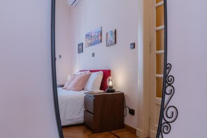 A bedroom with a bed, a nightstand, a wall-mounted lamp, and a door with a decorative metal frame. - Galliari Comfort Home by Wonderful Italy (Turin)