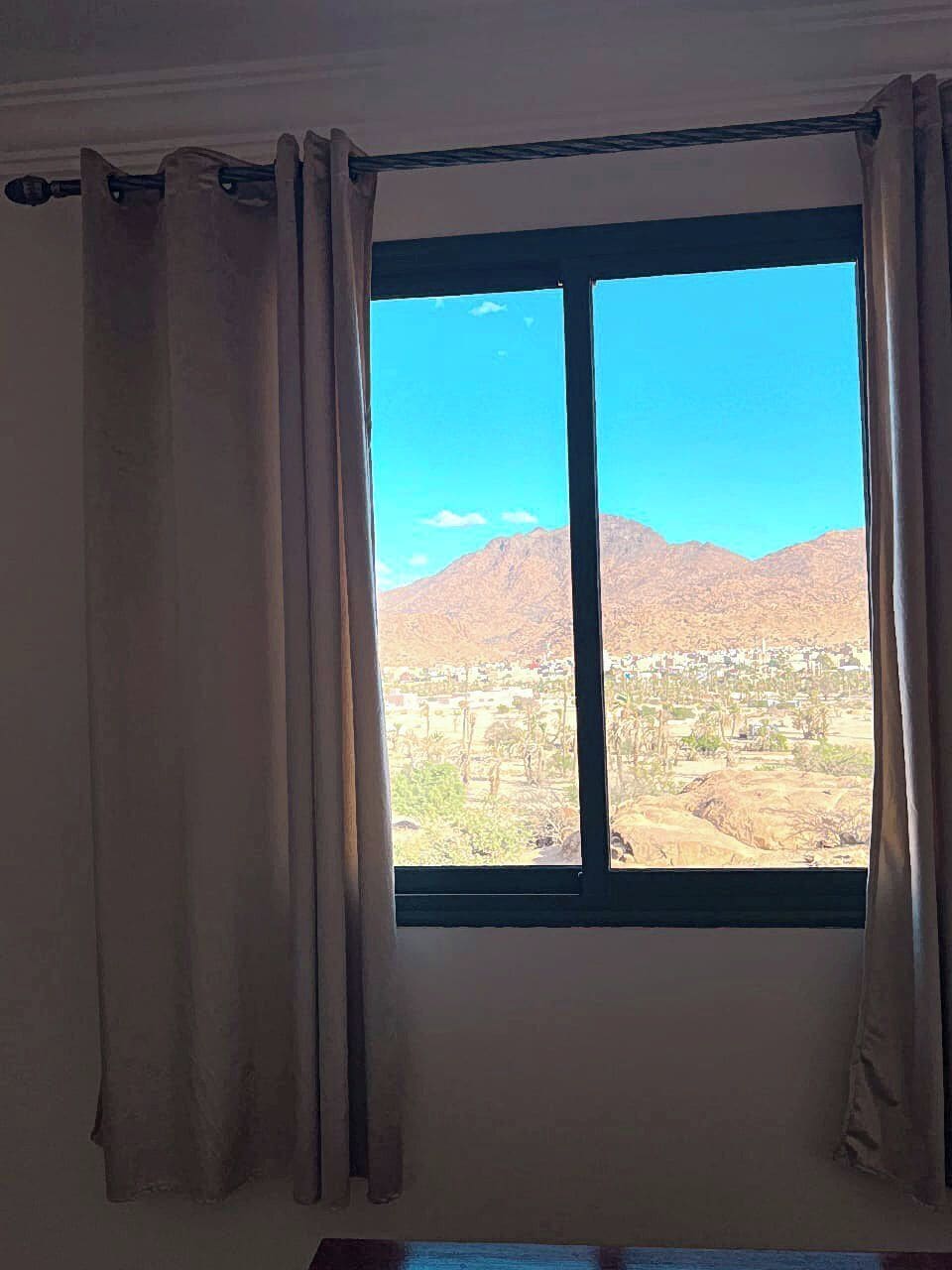 Ein Fenster mit Blick auf einen Berg und eine Stadt.