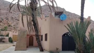 A building with a flat roof, a satellite dish, and a gated entrance.