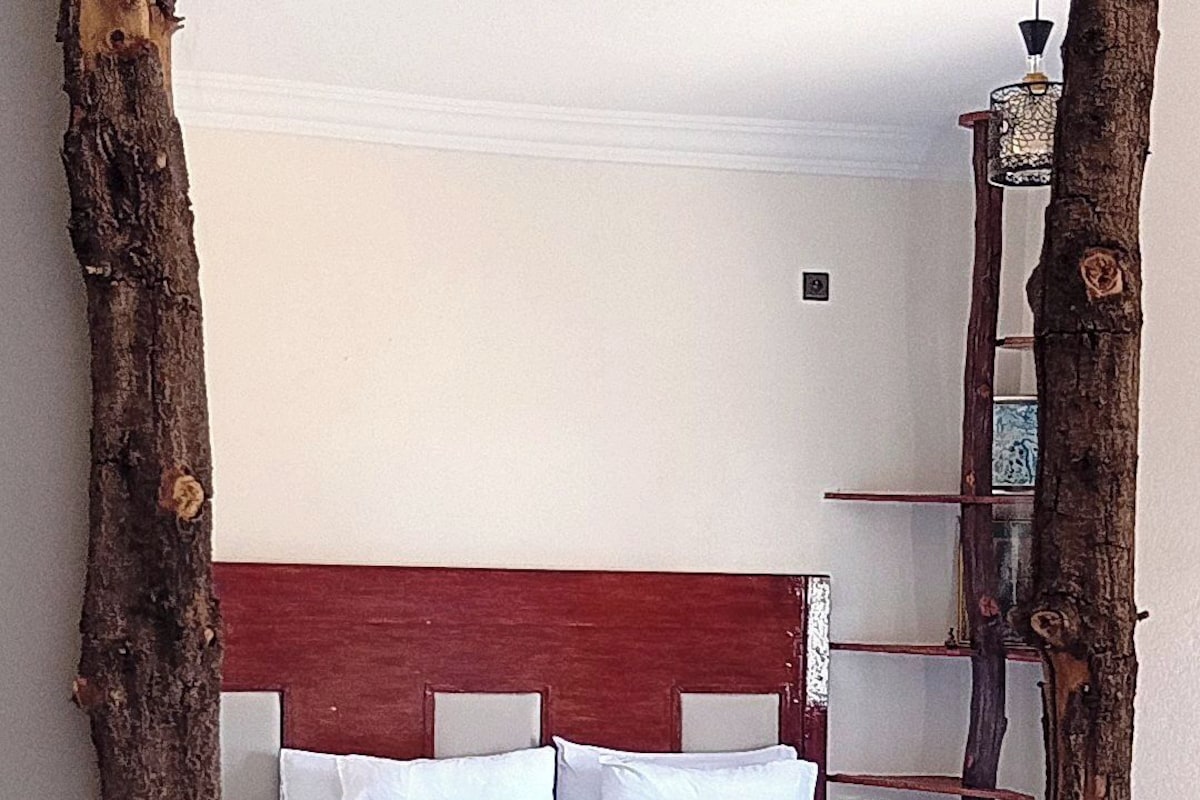 Ein Bett mit blauer Bettdecke und weißen Kissen, eingebettet in eine rustikale Holzkonstruktion.