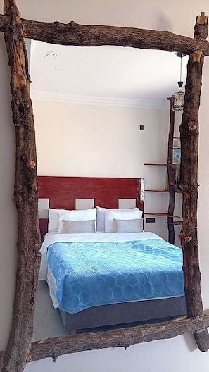 Ein Bett mit blauer Bettdecke und weißen Kissen, eingebettet in eine rustikale Holzkonstruktion.