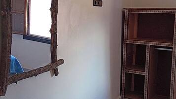 Une pièce avec un miroir rustique, une petite table en bois et un meuble agrémenté d’un cadre décoratif.