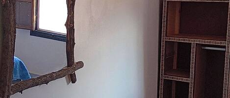 A room with a rustic mirror, a small wooden table, and a cabinet with a decorative frame.